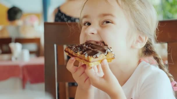 Küçük tatlım tüm çikolata ile bulaşmış, çocuk bir restoranda oturan ve çikolatalı kek yeme — Stok video