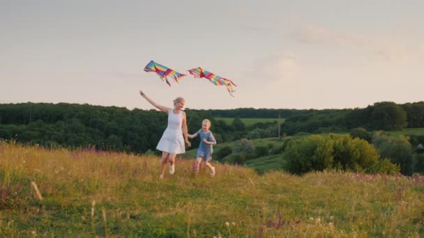 Een vrouw speelt met haar dochter - lopen rond in een cirkel met een vlieger van de lucht, het meisje is vrolijk proberen om hem te vangen. Gelukkige momenten van leven concept — Stockvideo