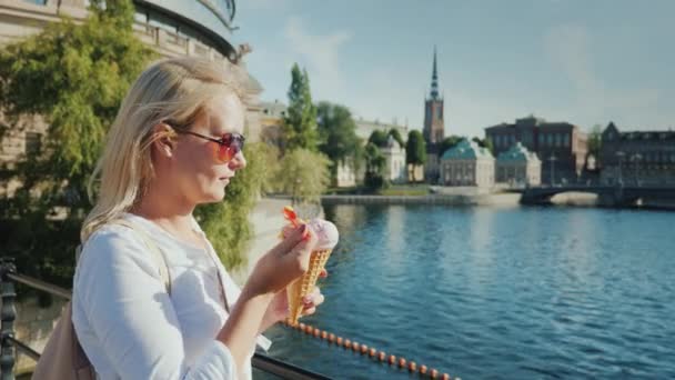 Kvinna turist äta glass på bakgrunden av vyn igenkännlig för Stockholms stad i Sverige — Stockvideo