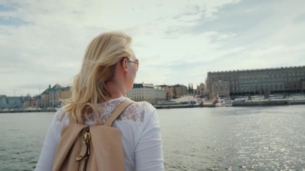 Uma mulher com uma mochila rosa admira uma bela vista da cidade de Estocolmo, na Suécia. Viagem através do conceito de Euprope — Vídeo de Stock