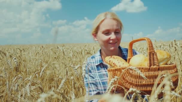 妇女农夫与一个篮子与面包和卷在成熟麦子领域。好收成, 有机产品理念 — 图库视频影像