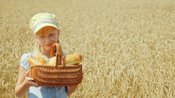 Retrato de una niña con una cesta de pan en un campo de trigo. Cosecha suficiente y buena — Vídeo de stock