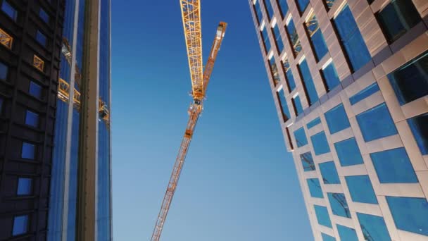 En vertiginously hög tornkran i centrum av den moderna staden. Roterande video. Byggandet av skyskrapor — Stockvideo