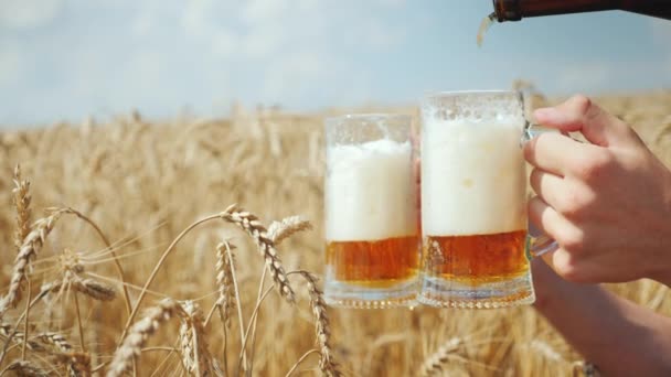 Versare una birra fresca in una tazza sul campo di grano dorato maturo. Per placare la sete e il concetto di prodotto biologico — Video Stock