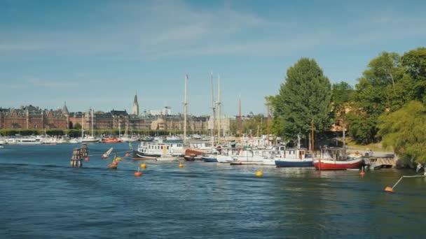 Quay em Sokholm, belos iates são ancorados, barcos com turistas estão nadando. Bela cidade europeia, a capital da Suécia — Vídeo de Stock