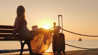 İri yarı bir çanta içinde bir ışık romantik bir kadın iskelede oturur, Güneş doğarken deniz ve uzakta yalnız bir gemi üzerinde görünüyor. Cruise ve kavram seyahat
