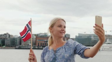 Bir Norveç bayrağı fotoğrafları kendini Oslo şehir çizgi arka planı olan bir genç kadın. Seyahat İskandinavya ve Norveç kavramı