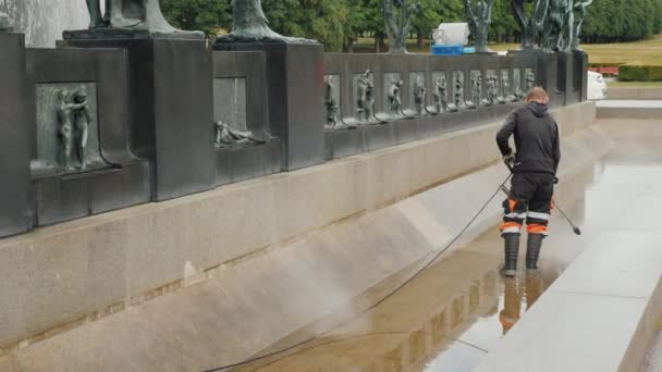 Oslo, Norvégia, 2018 július: A munkavállaló tisztítja a kút a szobor park Gustav Vigeland — Stock videók