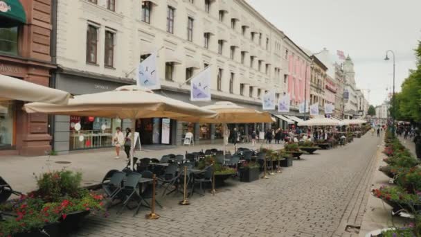 Oslo, Noorwegen, juli 2018: Een zicht langs de Karl Johans straat in de buurt van het Koninklijk Paleis. Een heleboel cafés en tabellen met paraplu's op de straat, een menigte van voorbijgangers — Stockvideo