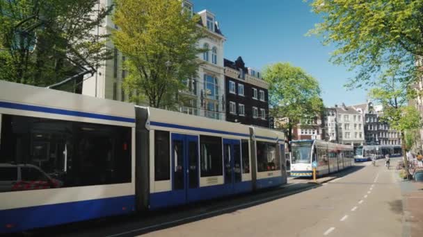 Amesterdam, Netherlands, May 2018: Public transport in Amsterdam. On a picturesque street with old houses there is a tram ride — Stock Video