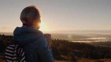 Gezgin Güneşin ufukta hayran dağın, sıcak çay içer. Norveç'in doğa