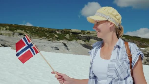 눈이 피크에 노르웨이의 국기와 함께 여자. 여름, 눈이 아직 녹아 하지. 관광 및 스칸디나비아 여행 — 비디오