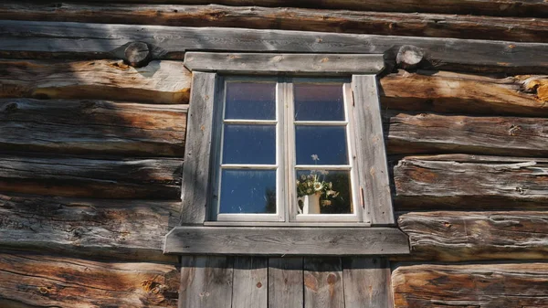 Window with flowers on a windowsill in an old wooden house — Stock Image Window with flowers on a windowsill in an old wooden house Stock Photo