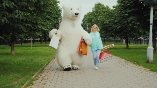 A young stylish girl is pleased with a good shopping together with her friend the big polar bear, they are cheerfully carrying the full packages of purchases
