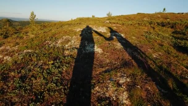 İki gezginler gölgeler el ele tutuşarak dağlık arazi yürüyor. Aktif yaşam tarzı — Stok video