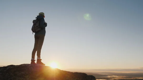 Crane shot: A woman traveler stands on top of a mountain, looks at the beautiful landscape ahead, admires the nature of Norway — Stock Photo, Image