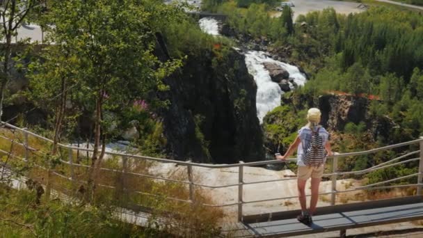 En kvinna ser ut på den majestätiska vattenfallet av Woringsfossen i Norge. Imponerande vackra Skandinaviska naturen — Stockvideo
