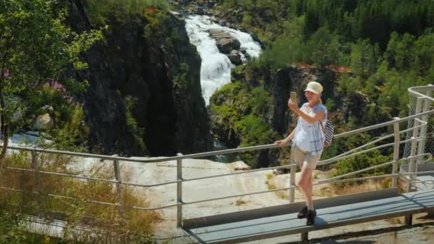 Bir kadın Woringsfossen Norveç'te görkemli şelale bakar. İskandinav doğanın etkileyici güzelliği — Stok video