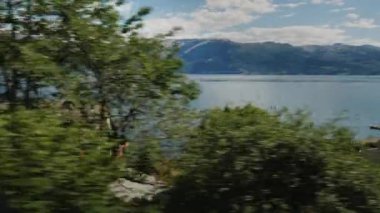 Sürücü pitoresk bir fiyort kıyı yeşil tepelerde geleneksel ahşap evler görebilirsiniz.