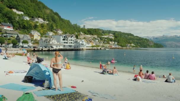 Oystesse, Norway, July 2018: Tourrists bathing and resting on a small beach amidst a picturesque fjord — стоковое видео