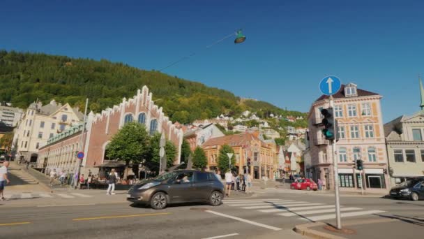 Bergen, Noorwegen, juli 2018: De drukke centrale straat van Bergen, intens verkeer en mensen. In de heuvels, pittoreske huizen — Stockvideo