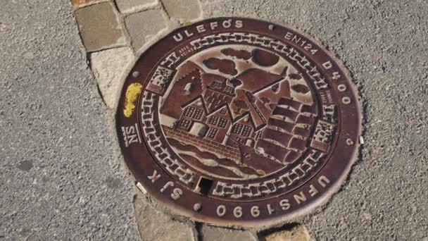 Bergen, Norway, July 2018: Metal sewer hatch with images of houses and sailboats. Original decoration of the city in Bergen — Stock Video