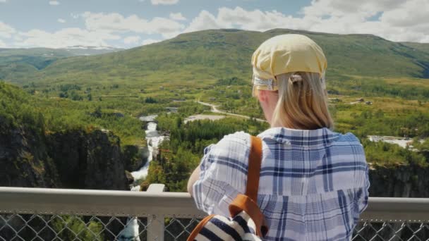 Steadicam shot: Una mujer mira la majestuosa cascada de Woringsfossen en Noruega. Impresionante belleza de la naturaleza escandinava — Vídeo de stock