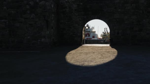 Puerto marítimo a través del arco de la antigua muralla de la fortaleza. La sombra crea un hermoso óvalo en el suelo. Steadicam tiro — Vídeos de Stock