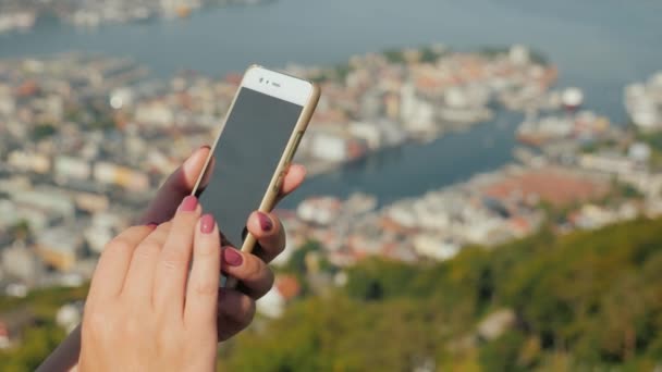 Mãos femininas com um smartphone. Use o telefone no fundo da cidade de Bergen — Vídeo de Stock