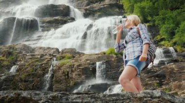 Aktif kadın Twindefossen şelale Norveç'te çerçevede temiz suyu içer