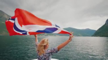 Büyük bir Norveç bayrağı etkin bir kadınla bir yolcu gemisi yay üzerinde duruyor. Norveç fiyordu cruise