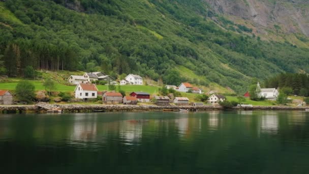 Een schilderachtig dorp met traditionele houten huizen aan de oever van de fjord in Noorwegen. Uitzicht vanaf een drijvende cruise liner — Stockvideo