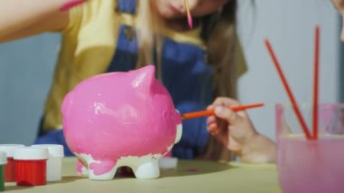 Çocuk kumbara pembe boya ile boyayın. Çerçevede görünür sadece ellerin