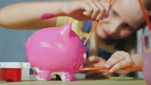 Kinderen schilderen vrolijk piggy bank. Gelukkige jeugd concept — Stockvideo