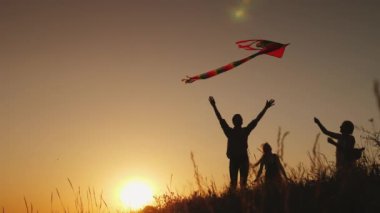 Bir uçurtma ile oynayan bir çocuk ailesiyle. Gün batımında güzel bir yerde. Yaz etkinliği ve tatil