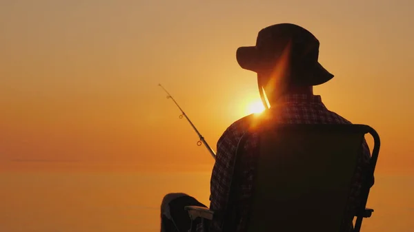 Un jeune homme est assis au bord de la mer, à pêcher. Détente en plein air — Photo