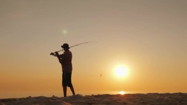 Gölün içine kaşık-yem döküm balıkçı, silüeti