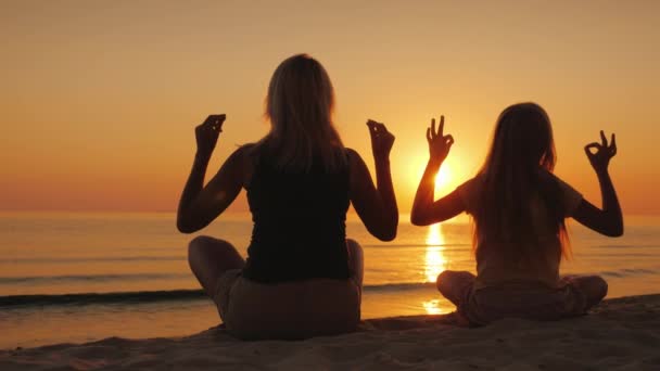 Μαμά και κόρη διαλογισμό δίπλα στη θάλασσα στο ηλιοβασίλεμα. Υγεία και μαζί χαρούμενη ώρα — Αρχείο Βίντεο