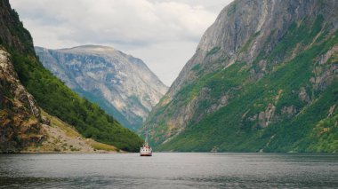 Bir pitoresk görüntülemek Neroy-fiyort Norveç'te ön planda küçük bir tekne, arkasında yüksek dağlar ve bulutlar