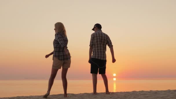 Uma mulher e seu filho adolescente dançam juntos uma dança engraçada na praia. Aprender movimento de dança na moda — Vídeo de Stock