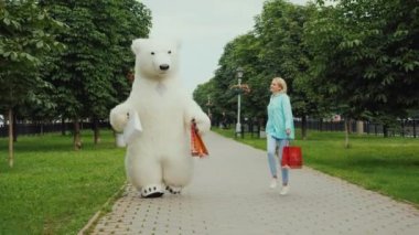 Bir büyük dostu kutup ayısı, marketten satın almalarla ev paketleri taşıyan genç bir kız ile birlikte. Neşeli alışveriş