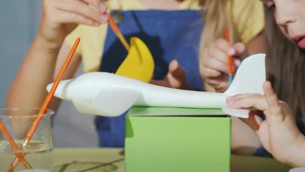 Las manos de los niños con cepillos pintan el modelo de la aeronave. Desarrollo de juegos con niños — Vídeo de stock