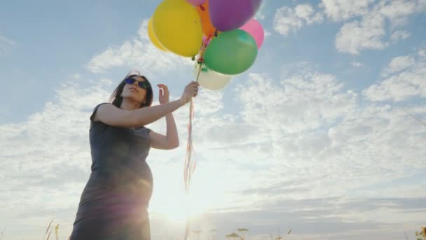 Молодая беременная женщина беззаботно играет с воздушными шарами — стоковое видео