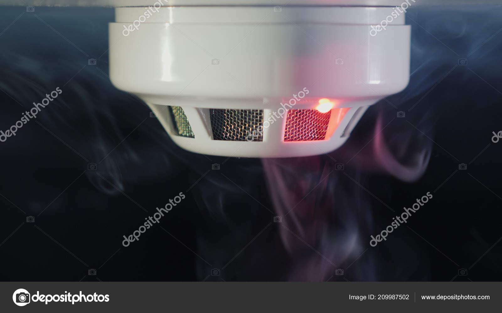 The smoke detector is triggered by a fire. Smoke and flames are visible — Stock Photo