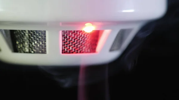 Close-up shot: The smoke detector is triggered by a trickle of dum, the red indicator lights up — Stock Photo, Image