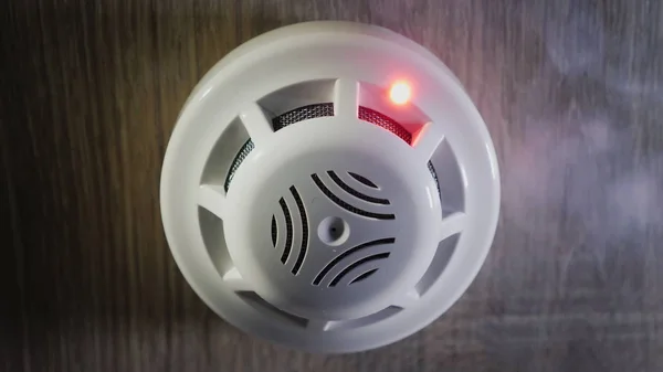 Low angle shot: The smoke detector is triggered by a trickle of dum, the red indicator lights up — Stock Photo, Image