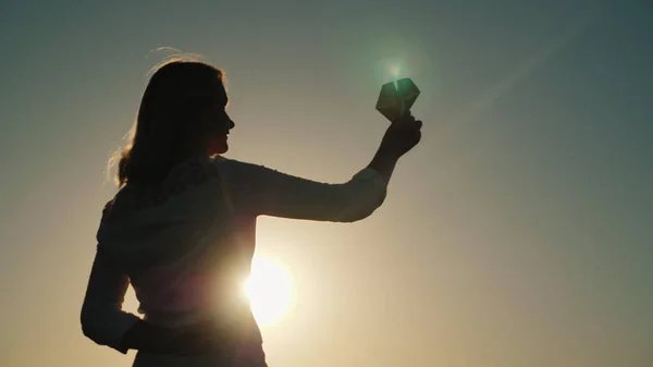 Uma mulher de meia-idade está brincando com um avião de papel ao pôr-do-sol. Sonhos e conceitos de infância — Fotografia de Stock