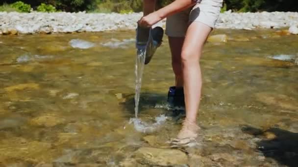 Una mujer vierte agua de su bota, empapa sus pies — Vídeos de Stock