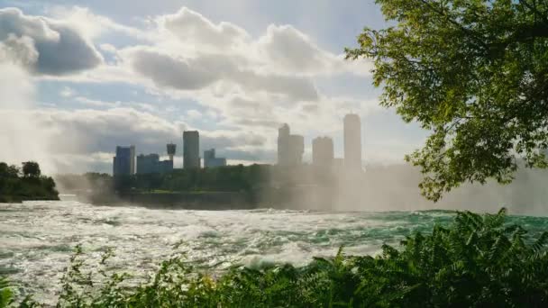 Floden Niagara framför vattenfallet. Det syns den kanadensiska kusten med byggnader av hotell och underhållande centers for touris — Stockvideo