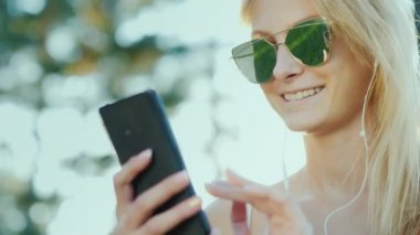 Mutlu bir smartphone kadın güneş gözlüğü kullanın. Tatile, güneş ışınlarının güzel saçlarını aydınlatmak
